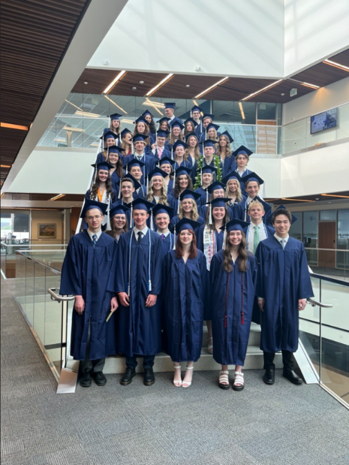 A group of people in graduation gowns and caps posing for a photoDescription automatically generated